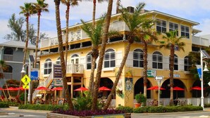 A two-story building with balconies, red umbrellas, and a sign for 'Brige Street Bistro'.
