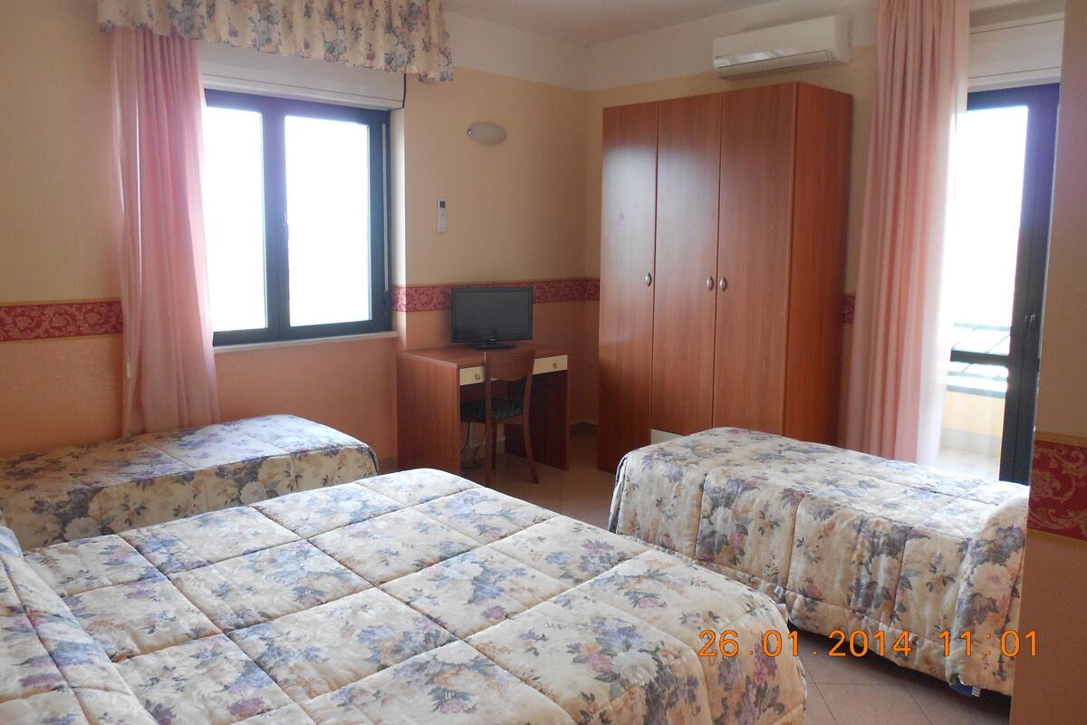 Una habitación de hotel con dos camas, un escritorio, una televisión y un armario.