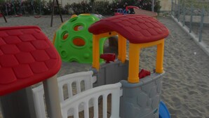 Eine Kinderspielanlage mit rotem Dach, weißen und grauen Wänden und einer blauen Basis.