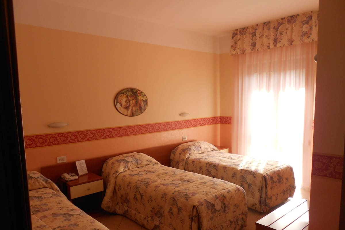 Una habitación de hotel con dos camas, una mesita de noche, un teléfono y una lámpara fijada a la pared.