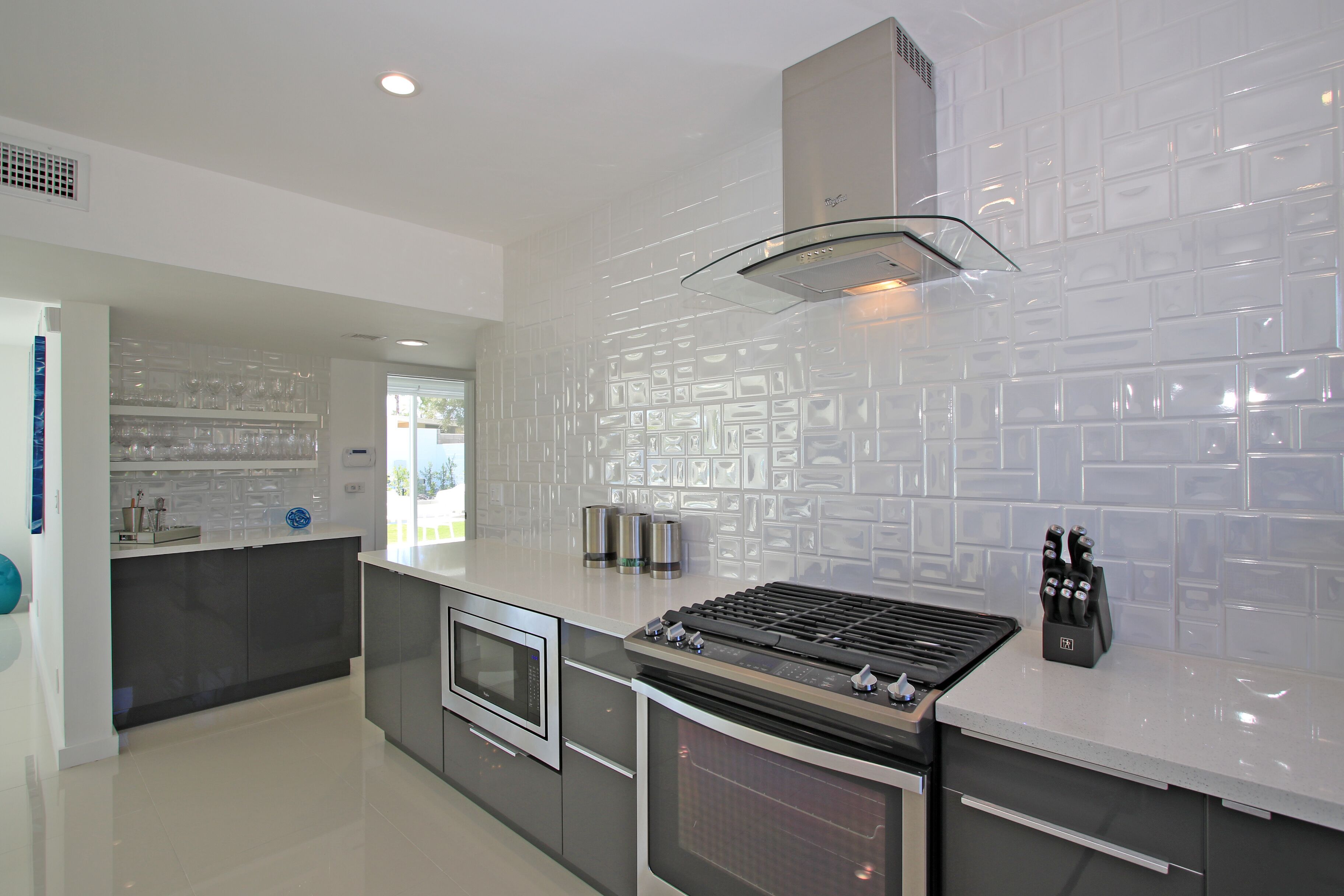 A modern kitchen with a central island, built-in oven, and a stainless steel range hood.