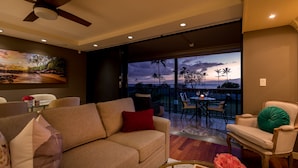 Un salon comprenant un canapé, des fauteuils, une table à manger et un balcon avec vue sur l’océan.