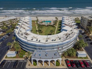 Stunning ocean views surround this hotel, featuring a central courtyard with a pool and lush greenery, and a modern design with a curved roof.
