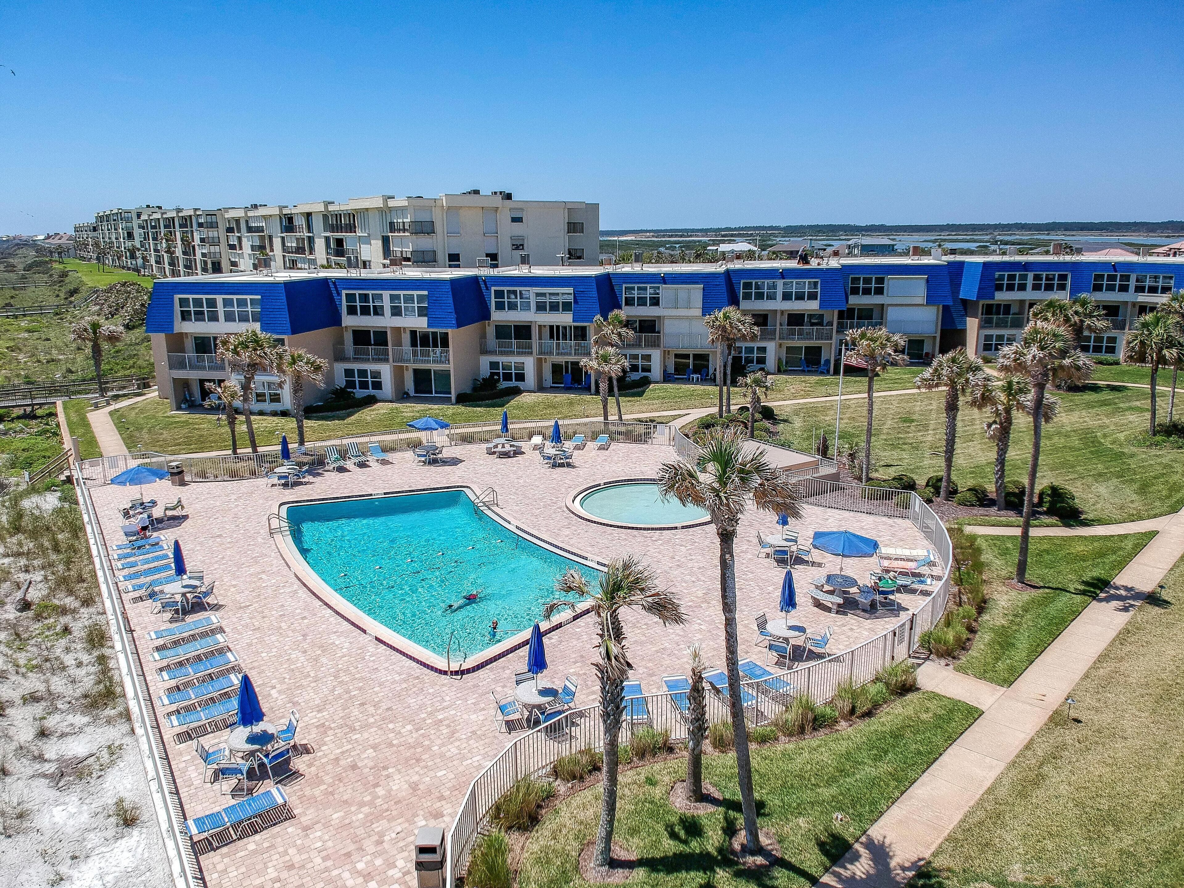 Ein Hotel mit Poolbereich, mehreren Liegestühlen und Meerblick.