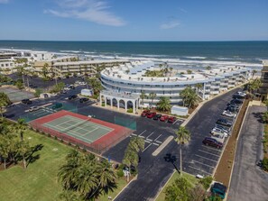 Un hôtel situé sur la côte, doté d’un bâtiment circulaire, d’un court de tennis et d’un parking.
