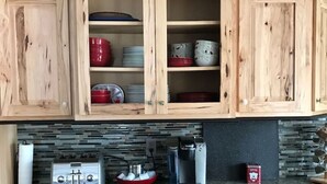 Une cuisine avec des meubles de rangement en bois, un grille-pain, une machine à café et un récipient rouge en forme d’ours.