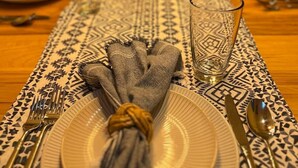 Une table à manger dressée avec des assiettes, des couverts et un centre de table.