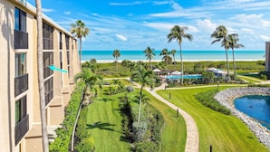 Een resort met een zwembad, palmbomen en uitzicht op het strand.