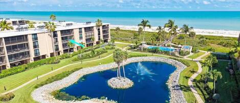 A hotel with a pool, palm trees, and a view of the beach.