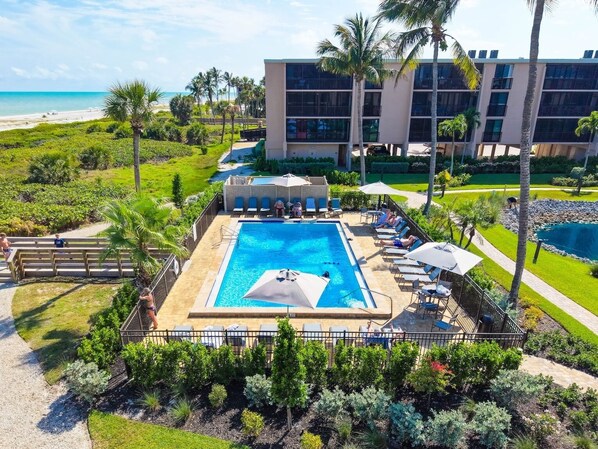 Et resort med swimmingpool, liggestole og udsigt til stranden.