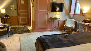Un dormitorio acogedor con cama, una silla, un escritorio, un televisor y una puerta.