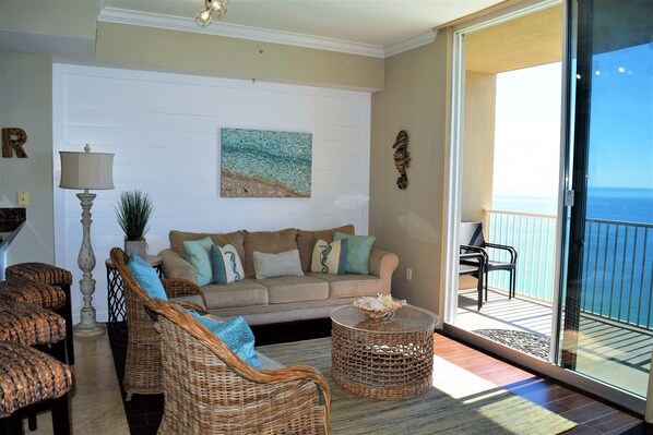 A living room with a sofa, wicker chairs, a lamp, and a painting on the wall. - Tidewater! Newly remodeled beach front luxury condo with beach servic (Panama City Beach)