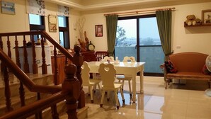 A dining area with a table and chairs, a staircase, and a sofa. - Sweetlight B&B (Jiaoxi)