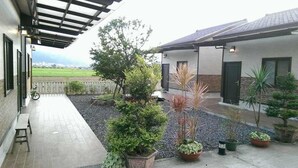 A covered patio area with a bicycle, potted plants, and a view of a green field. - Sweetlight B&B (Jiaoxi)