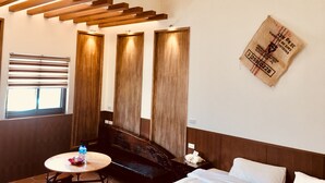 A hotel room with a wooden bench, a round table with water bottles, a bed with white linens, and a wall-mounted light fixture. - Sweetlight B&B (Jiaoxi)