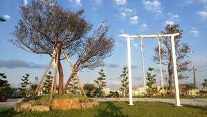 A park with a swing set, trees, and a white fence. - Sweetlight B&B (Jiaoxi)