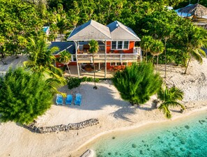 A beachfront property with a two-story building, a sandy beach, and palm trees. - Starfish Beach House  2BR Beachfront Retreat with Pool & Dock (Milton Bight)