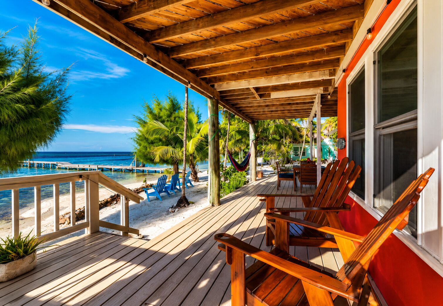 A wooden deck with outdoor seating, overlooking a beach and ocean.