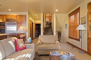 A living room with a sofa, armchair, coffee table, and a fireplace. There is a staircase leading to an upper level. - Outpost: Love Ridge 261 - Spacious, Air Conditioned (Jackson)