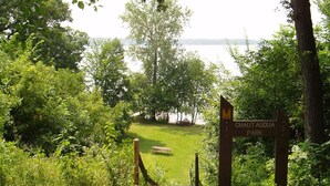 A park entrance with a sign for Chautauqua Park, a picnic table, and a grassy area leading to a body of water.