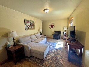 A living room with a sofa, a coffee table, a TV, and a star decoration on the wall.