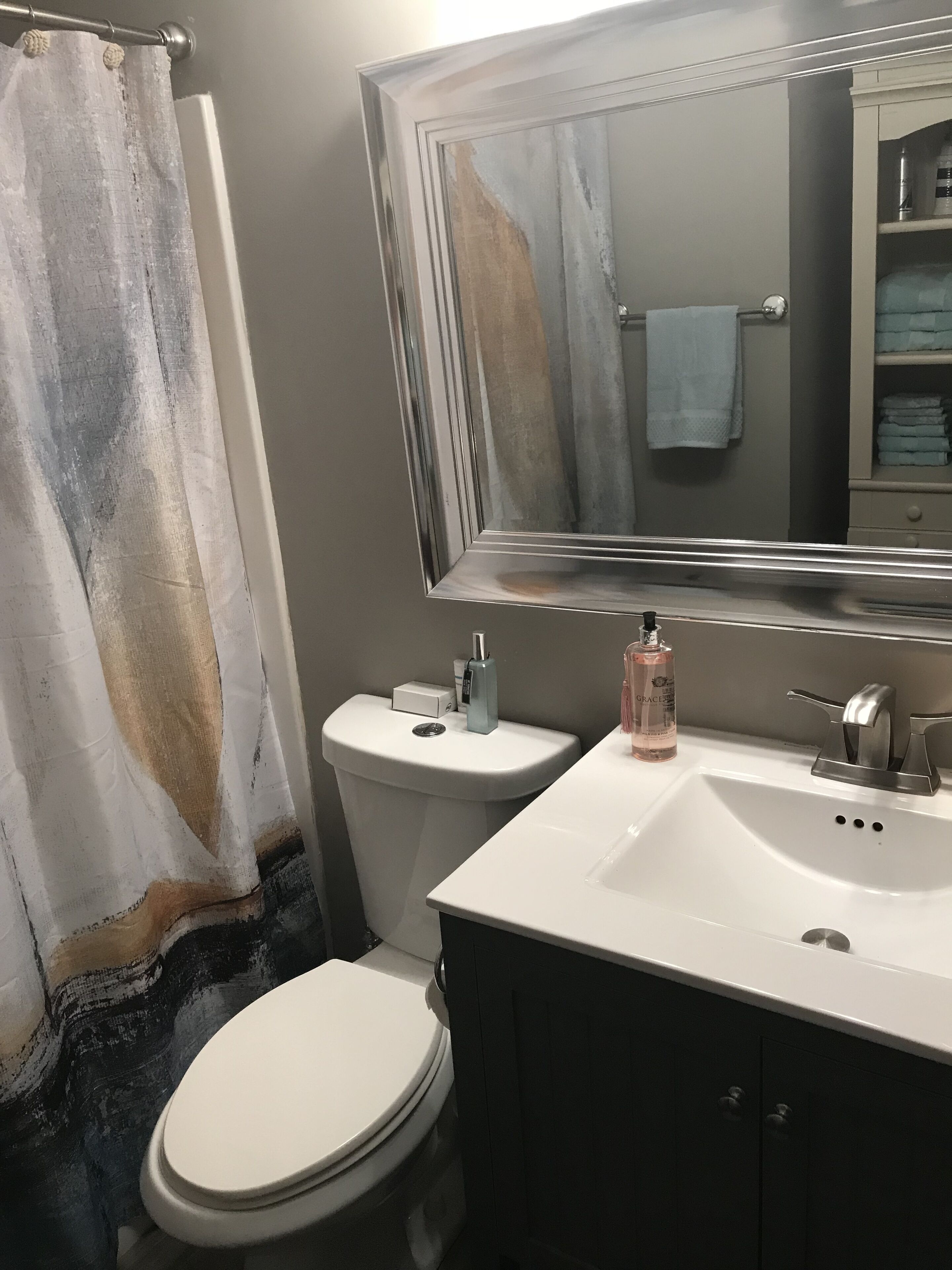 A bathroom with a toilet, sink, and mirror.
