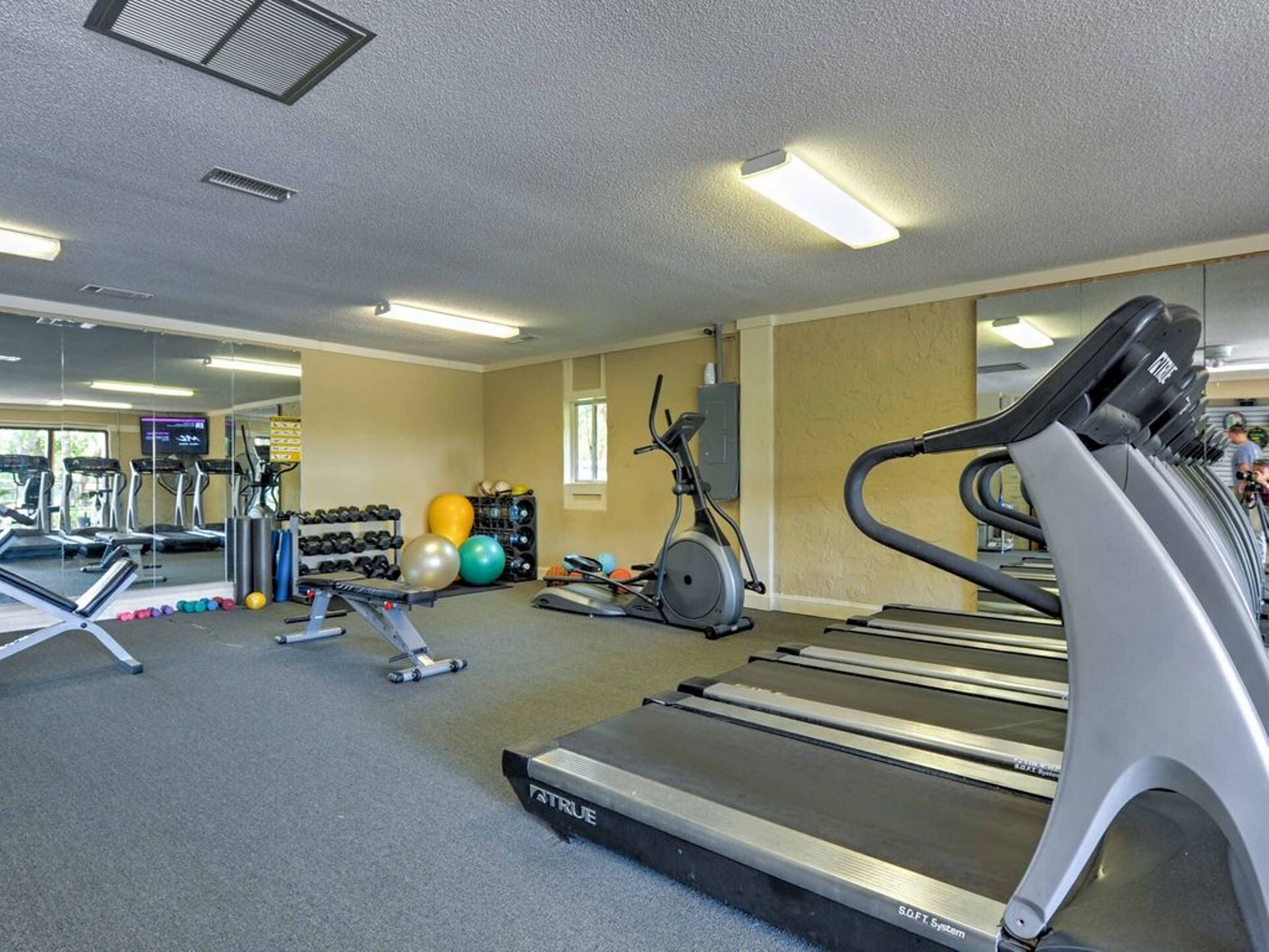 A gym with treadmills, exercise balls, and dumbbells.
