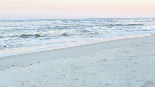 A beach with waves and a clear sky.