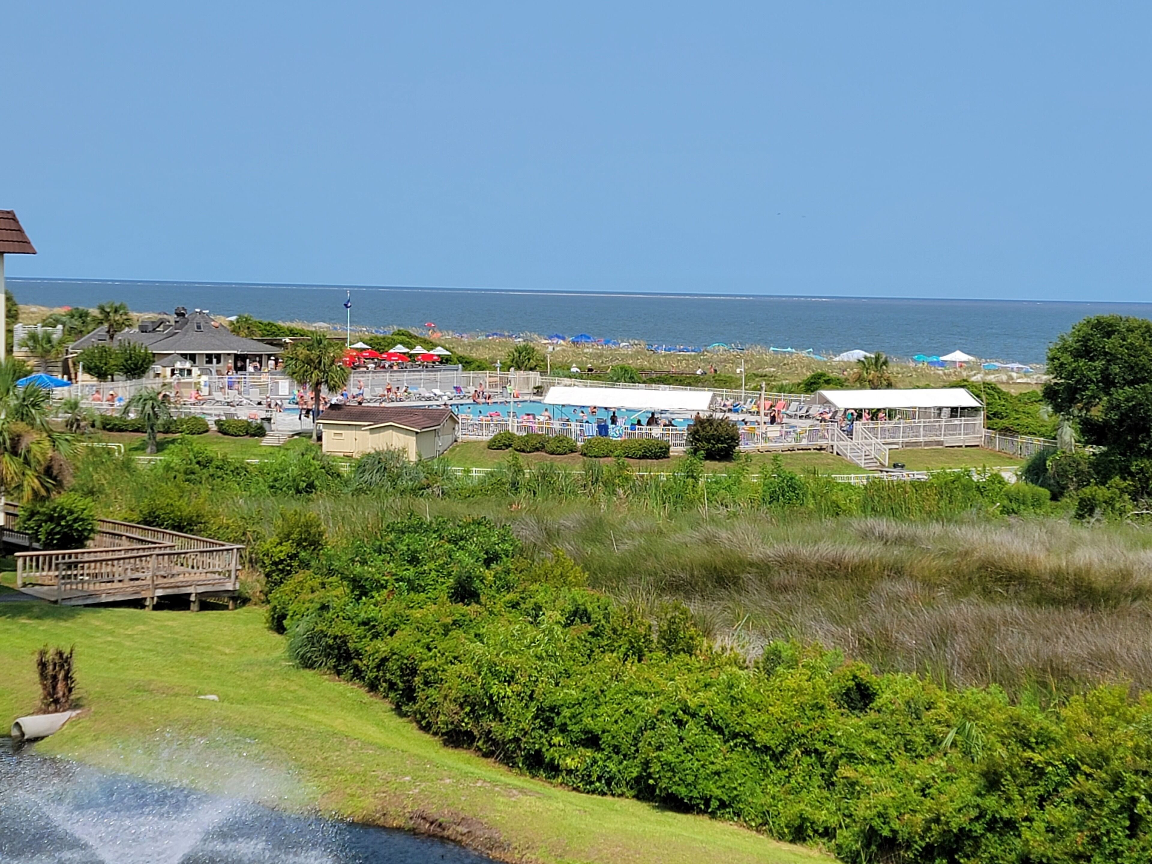 Un complejo turístico frente al mar con piscina, sombrillas de playa y vistas al océano.