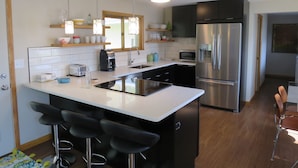 Een moderne keuken met een centraal eiland, roestvrijstalen apparatuur en barkrukken.