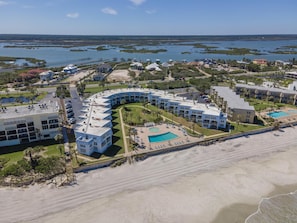 A resort with a curved building, a swimming pool, and a beach.