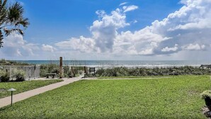 A grassy area with a pathway leading to a beach. - Sandpiper 228 - Paradise Found at Crescent Sandpiper 228 (St. Augustine)