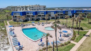 Un hôtel doté d’une grande piscine, de nombreux chaises longues et offrant une vue sur l’océan.