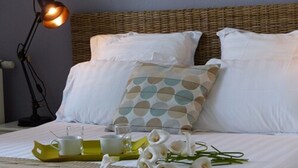 A neatly made bed with white linens, a wicker headboard, and a decorative pillow with a polka dot pattern. - Maison d'Hôtes du Domaine Fournié (Tarascon-sur-Ariege)