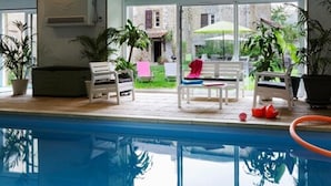 A poolside area with a clear view of the pool, white lounge chairs, and potted plants. - Maison d'Hôtes du Domaine Fournié (Tarascon-sur-Ariege)