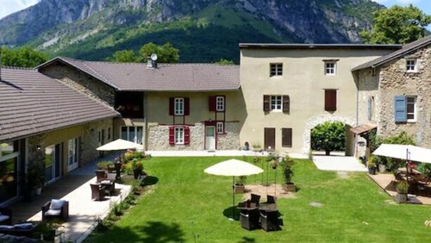 A courtyard with outdoor seating, a mountain backdrop, and traditional architecture. - Maison d'Hôtes du Domaine Fournié (Tarascon-sur-Ariege)