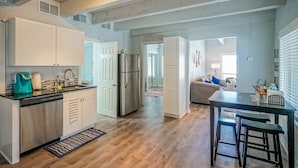 A modern kitchen with white cabinetry, stainless steel appliances, and a wooden floor.