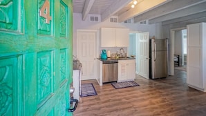 A kitchen with white cabinets, a stainless steel refrigerator, and a teal kettle.