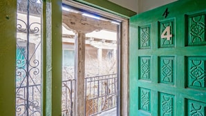 A green door with the number 4, a wooden door frame, and a metal gate with decorative patterns.