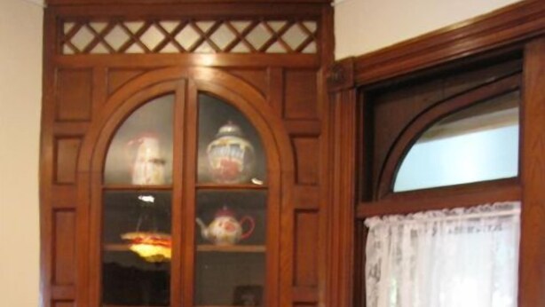A room with a wooden cabinet with glass doors, a brown armchair, and a window with a white curtain. - Historic Civil War house, great for family getaways.   (Gettysburg)