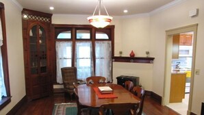 A dining room with a wooden table, chairs, a chandelier, and a view of the kitchen through a doorway. - Historic Civil War house, great for family getaways.   (Gettysburg)