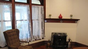 A room with a wooden floor, a brown armchair, a fireplace, and a shelf with decorative items. - Historic Civil War house, great for family getaways.   (Gettysburg)