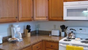 A kitchen with wooden cabinets, a white stove, and a microwave. - Historic Civil War house, great for family getaways.   (Gettysburg)