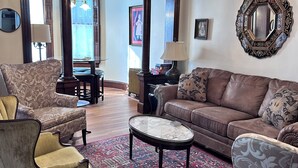 A living room with a chandelier, a brown sofa, patterned armchairs, a coffee table, and a large mirror. - Spectacular Family Getaway!  (Gettysburg)