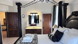 A hotel room with a large bed, a vanity with a mirror, and a chandelier. - Spectacular Family Getaway!  (Gettysburg)