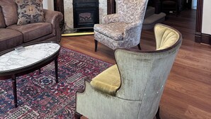 A living room with a fireplace, a chandelier, a sofa, a patterned armchair, and a coffee table. - Spectacular Family Getaway!  (Gettysburg)