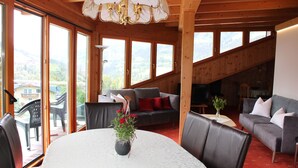 A spacious room with a large table, comfortable seating, and a view of the outdoors. - Apartment Hotel Panorama (Wagrain)
