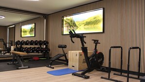 A gym with exercise equipment, a bench, and a large mirror. - Apartment Hotel Panorama (Wagrain)