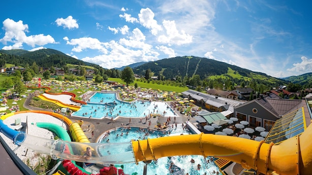 A water park with multiple pools and slides, surrounded by houses and mountains. - Apartment Hotel Panorama (Wagrain)