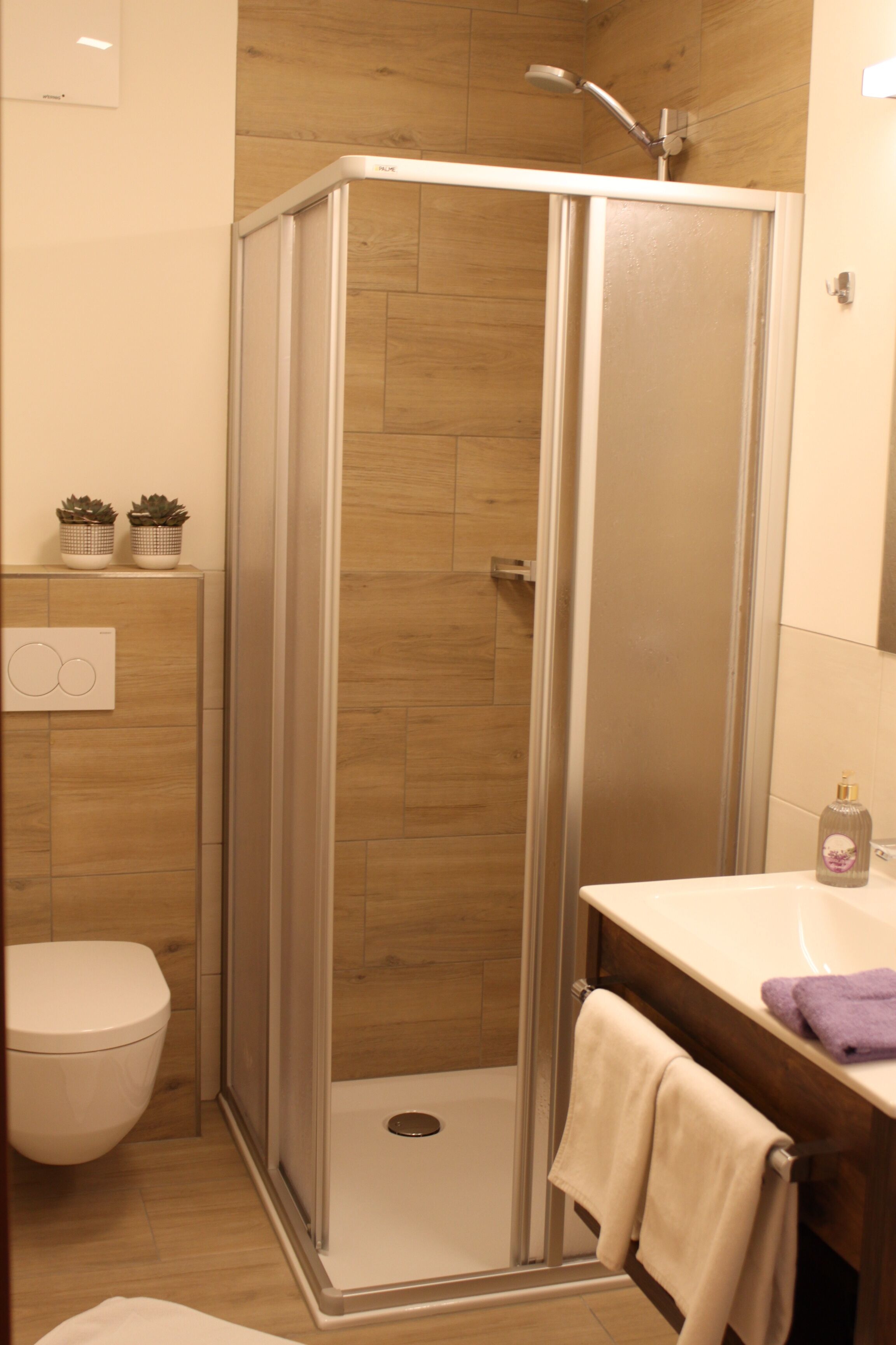 A modern bathroom with a glass shower enclosure, a toilet, and a sink with a towel.